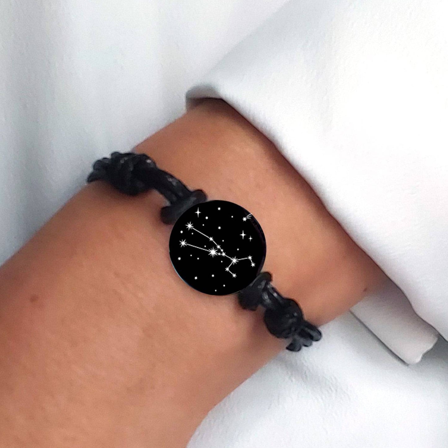 Black bracelet with a star constellations design on a wrist against a white background