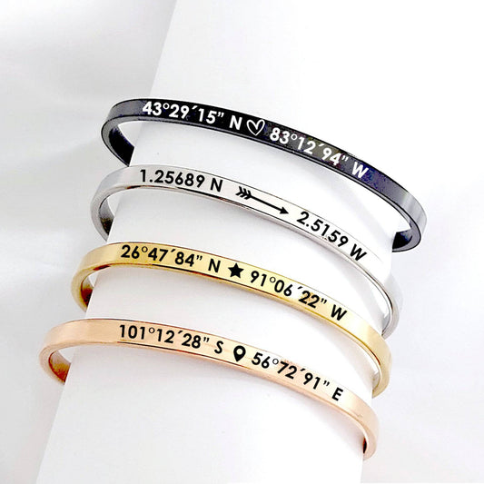 Set of four bracelets in different colors with engraved coordinates on a white background.