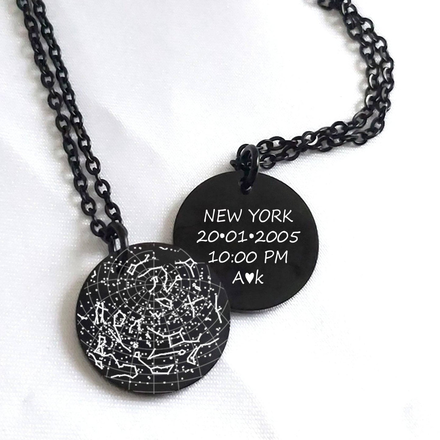 Black necklace with engraved disc and constellation design on a white background