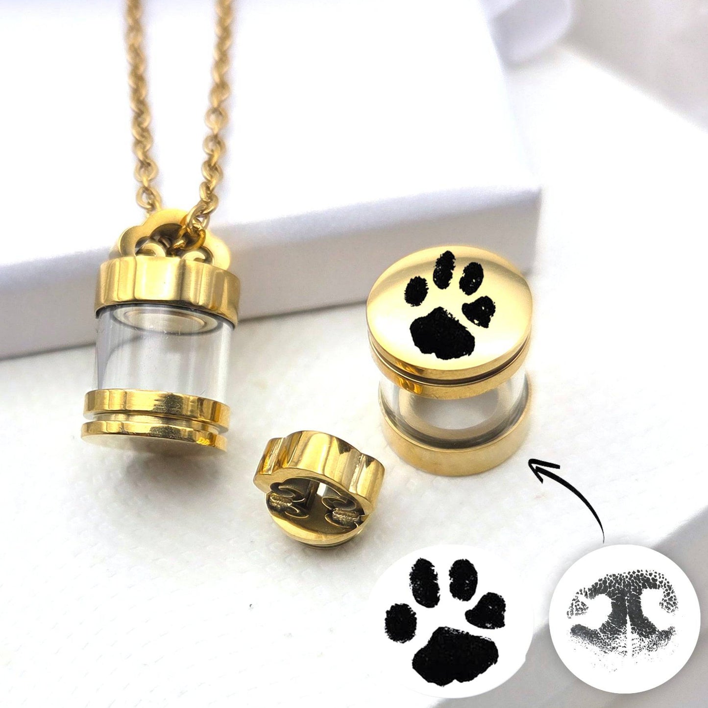 Gold pet urn necklace with paw print design on a white background