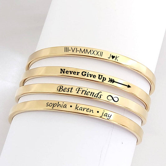 Set of gold bracelets with engraved text on a white background