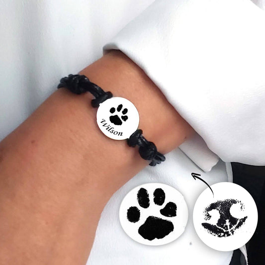 black later strap bracelet with a paw print charm on a wrist