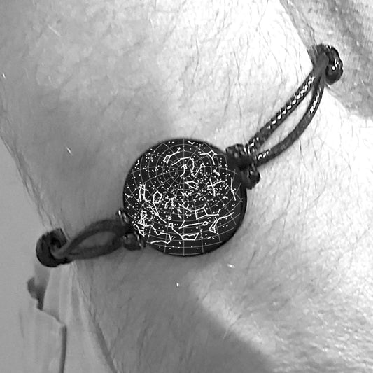 Black bracelet with a textured round charm on a person's wrist, against a light background.