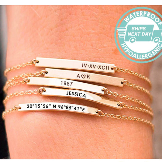 Gold bracelets with engraved text on a wrist, featuring a 'Waterproof' label.