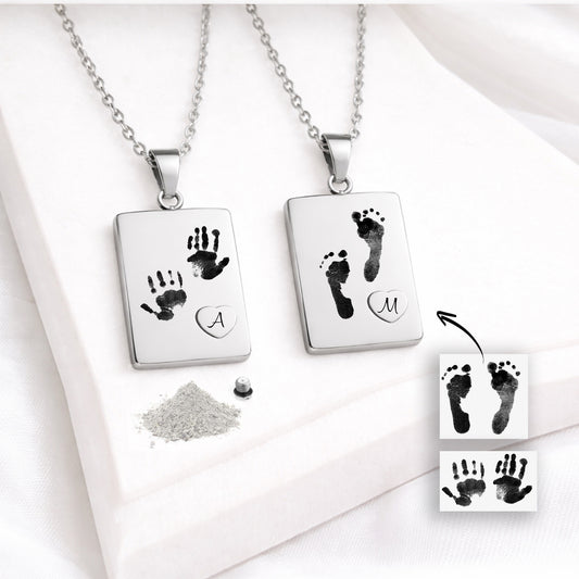 with two baby handprints and a raised heart containing the letter “A.” The other features two baby footprints and a heart with the letter “M.” Handprint and footprint reference images, ashes and a threaded screw are also visible.