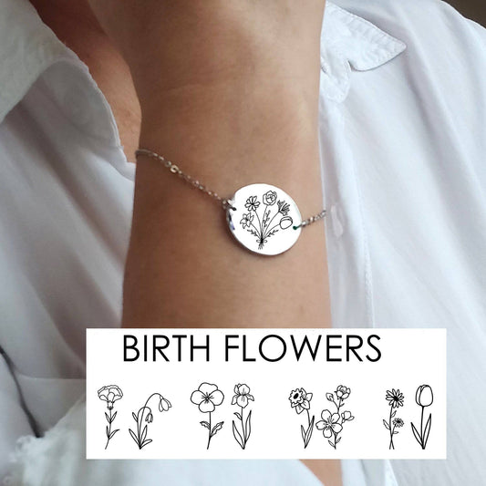 Silver coin bracelet on wrist against a white shirt background engraved with a bouquet of birth flowers 