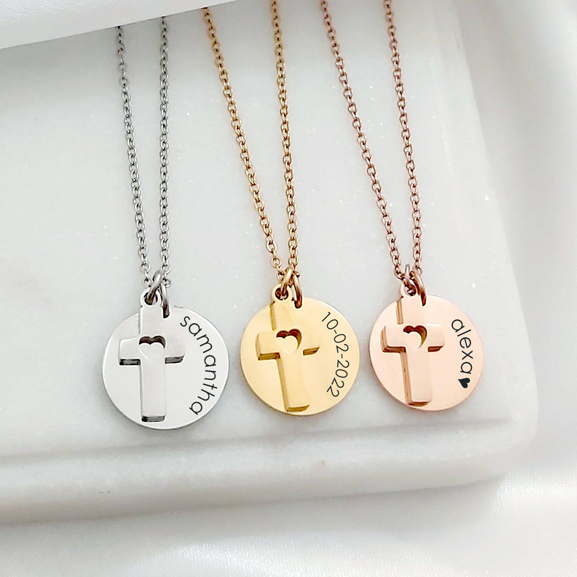 Three necklaces with cross pendants and engraved names on a white surface