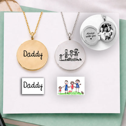 Two necklaces with engraved text on a green book with a pen and cards on a white satin background