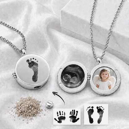 Open round silver-tone memorial urn locket with two circular photo spaces inside and tiny baby footprints, a name and a small heart precisely engraved on the polished front.