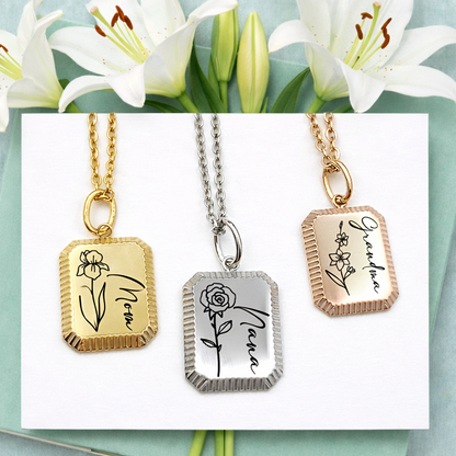 Three necklaces with engraved names and floral designs on a card with white lilies.