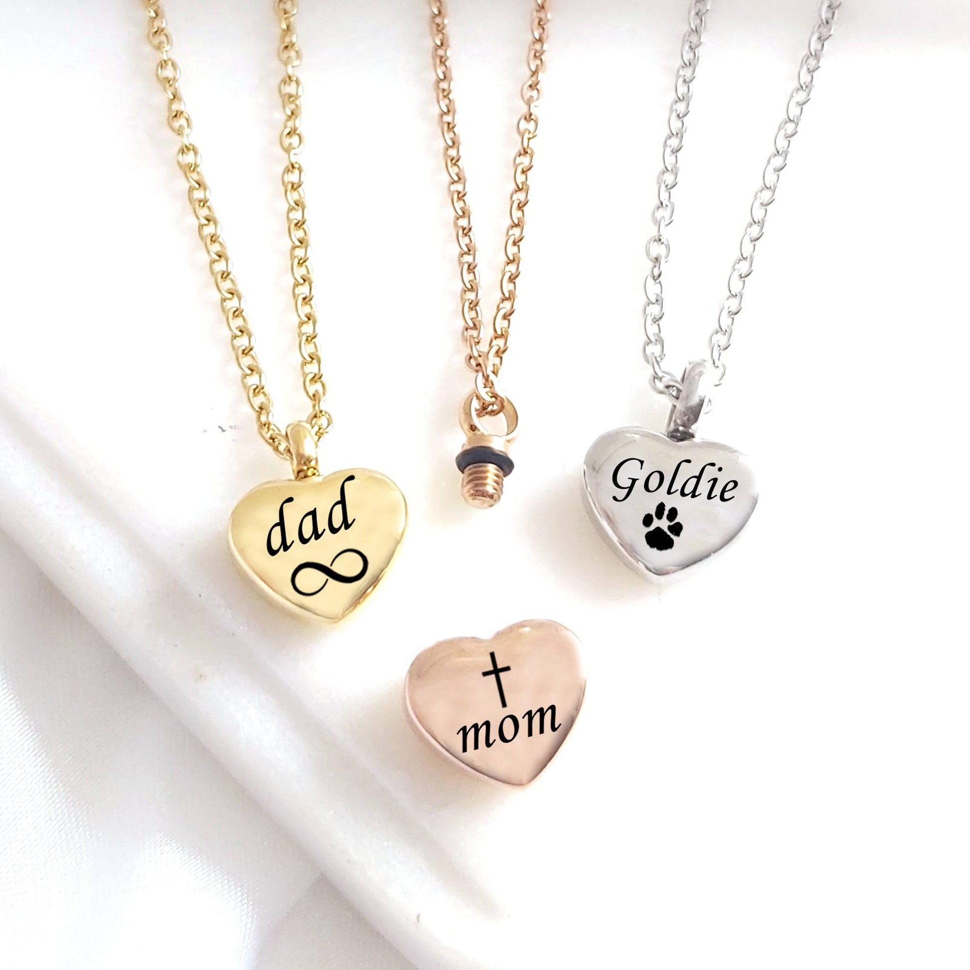 Heart-shaped pendants on gold chains with engraved text on a white background